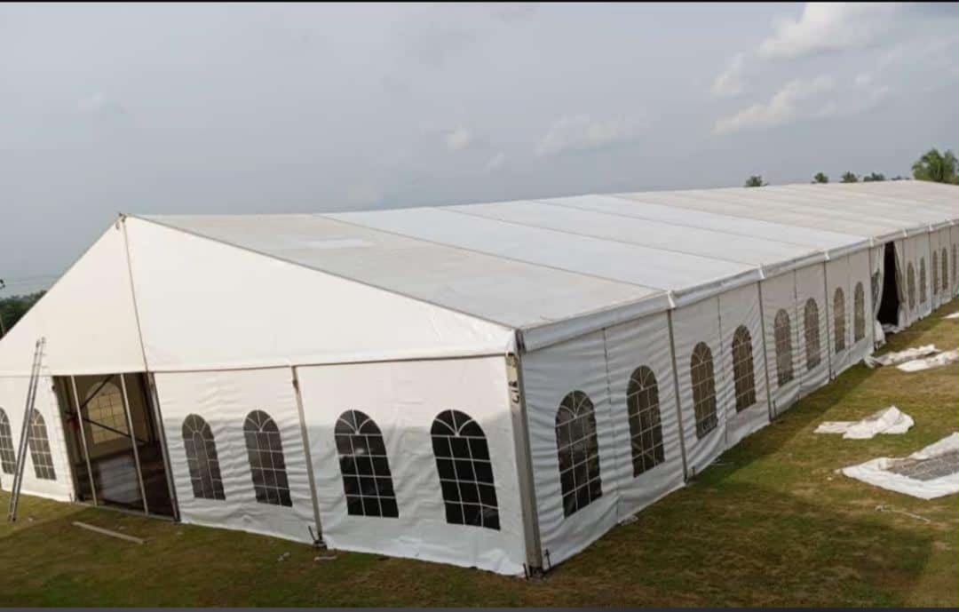 Long white marquee tent with arched windows on a grassy field